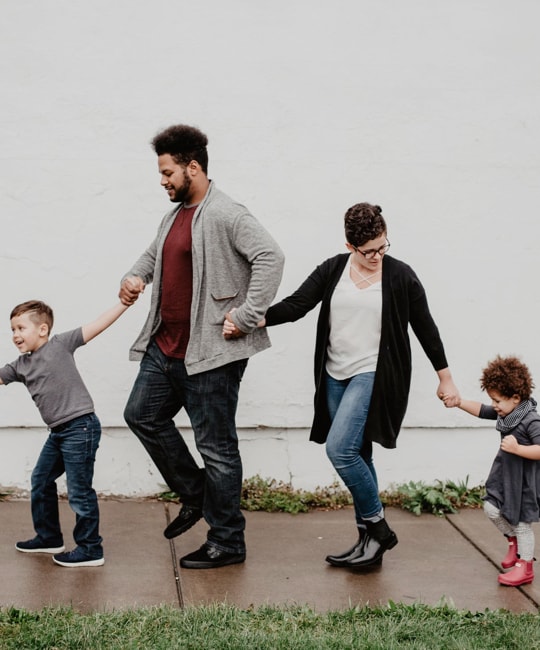 A family of four walking in line and holding hands